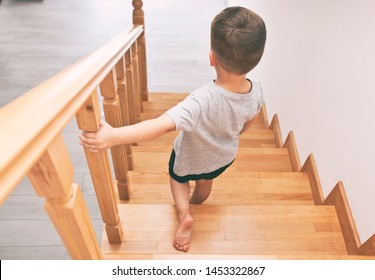 The Child Is Moving Down Through The Wooden Stairs In Home