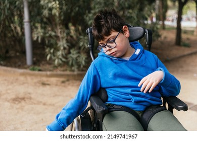 Child With Multiple Disabilities In A Wheelchair Enjoying The Day Outdoors In The Park.