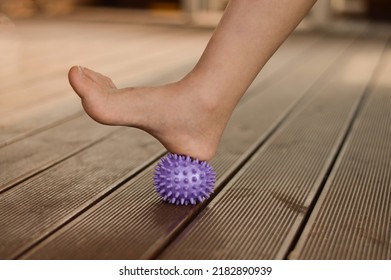 Child myofascial relaxation of the muscles of the foot with a massage purple ball at home, close-up. Prevention of flat feet in childhood - Powered by Shutterstock