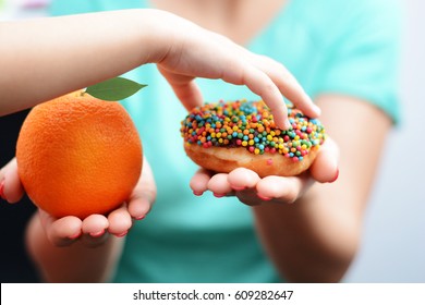 Child Obesity Concept With Little Girl Hand Choosing A Sweet And Unhealthy Doughnut Instead Of A Fruit