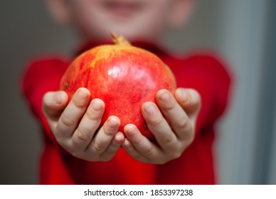 A child offering pomegranate. Child holds a pomegranate in his tiny hands. - Shutterstock ID 1853397238
