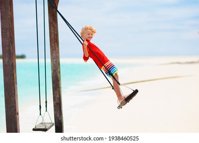 Child On Beach Swing. Kid Swinging On Tropical Island. Travel With Young Children. Summer Family Exotic Vacation. Kids Play On Sea Shore. Little Girl And Boy Playing In Luxury Ocean Resort.