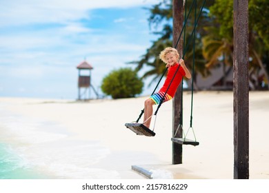 Child On Beach Swing. Kid Swinging On Tropical Island. Travel With Young Children. Summer Family Exotic Vacation. Kids Play On Sea Shore. Little Girl And Boy Playing In Luxury Ocean Resort.