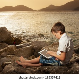 Child On The Beach With Tablet Computer