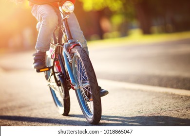 Child On A Bicycle At Asphalt Road In Early Morning. Boy On Bike In The City