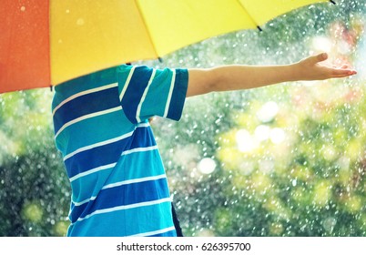 Child on rainy weather. Boy holding colourful umbrella under rain in summer - Shutterstock ID 626395700