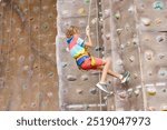 Child on rock climbing course. School boy bouldering. Extreme sport for kids. Children climb. Healthy outdoor activity. Active and brave teenager.