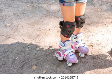 Child On Roller Skates In Protective Sportswear. Legs Close Up