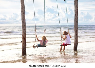 Child On Swing. Kid Swinging On Tropical Beach At Sunset. Travel With Young Children. Summer Family Vacation On Exotic Island. Kids Play On Sea Shore.