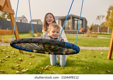 Child On Swing And Woman Kneeling On Lawn