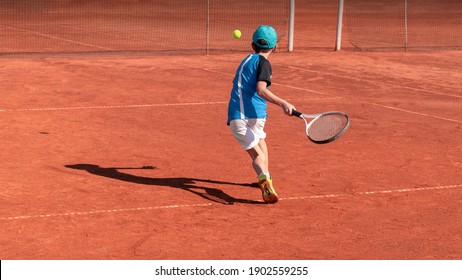 Child on tennis court. Boy tennis player learning to hit forehand . Physical activity and sports education of children. Tennis training at school or club. Background, copy space - Powered by Shutterstock