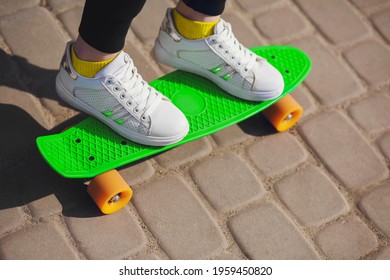 A child on vacation rides a green skateboard or pennyboard in the park. The health benefits of outdoor sports. Skateboard close up. Skateboarding is a great workout for body coordination and balance - Powered by Shutterstock