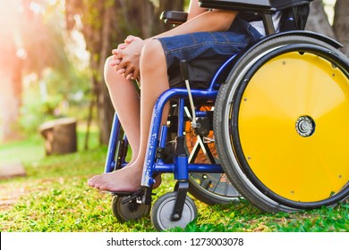 Child On The Wheelchair In The Park. Close-Up His Wheel.