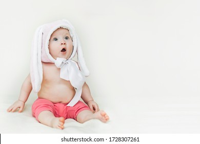 child opened mouth and looks up in surprise. background for sales, shocking news, children's goods. small beautiful baby sitter in rabbit hat.