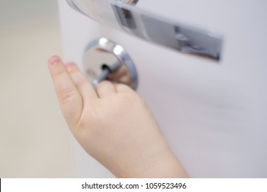 The child is opening the door. boys hand sticking out of closed door; little kid playing hide and seek game;