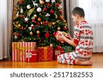 Child opening gift box under Christmas tree