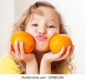 Child with oranges. Happy little girl with fruit at home.