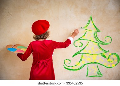 Child painting Christmas decorations. Kid playing at home. Xmas holiday concept