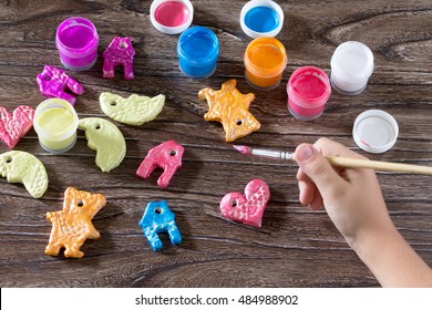 Child Painting Christmas Decorations From Salt Dough. Children's Art Project, A Craft For Children.