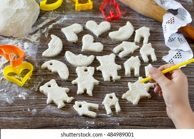 Child Painting Christmas Decorations From Salt Dough. Children's Art Project, A Craft For Children. Craft For Kids.