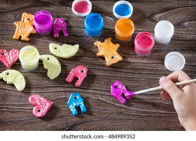 Child Painting Christmas Decorations From Salt Dough. Children's Art Project, A Craft For Children.