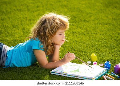 Child painting drawing art. Child boy painting with paints color and brush in park outdoor.