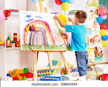 Child Painting At Easel In School. Education.