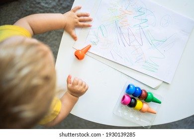 a child painting on a sheet on a table at home The child has col