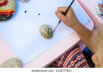 Child Painting Pebbles With Brush