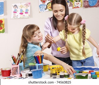 Child painting in preschool. Teacher help by little girl. - Powered by Shutterstock