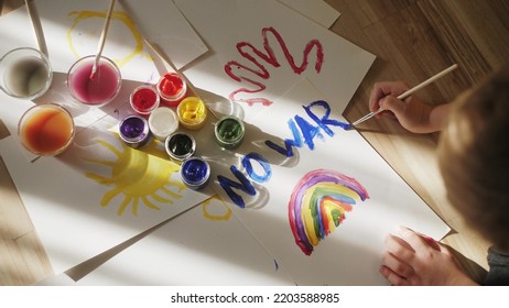 Child Painting Rainbow And No War With Gouache On A Piece Of Paper.