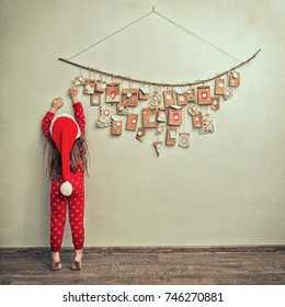child  in pajamas and Christmas cap stretches for advent calendar with small gifts