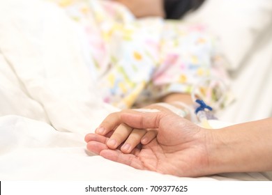 Child Patient With IV Line In Hand Sleep On Hospital Bed With Mother's Hand Holding Together To Support Ill Daughter.Medical Palliation Healthcare Concept