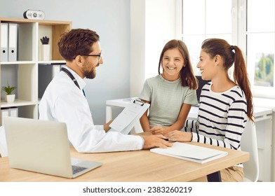 Child patient with mother at a medical examination in the doctor's office. Friendly pediatrician doctor giving consultation to a girl sitting at the desk in clinic. Pediatrics and kid's checkup. - Powered by Shutterstock