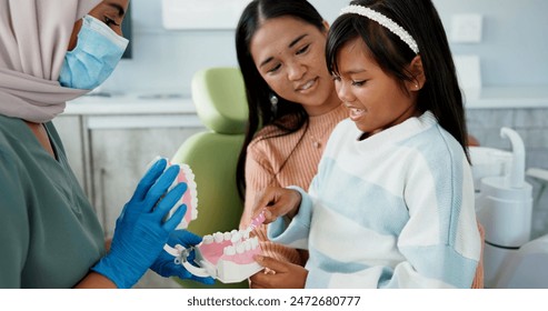 Child, pediatric dentist or teach on brushing teeth in practice or kid friendly demonstration of tooth hygiene. Orthodontist, parent or girl by dental model or cleaning mouth in interactive education - Powered by Shutterstock