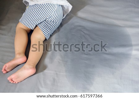 Child pee on a mattress,Little girl feet and pee in bed sheet,Child development concept ,selected focus at wet on the bed