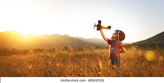 Child Pilot Aviator With Airplane Dreams Of Traveling In Summer In Nature At Sunset
