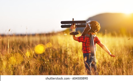 Child pilot aviator with airplane dreams of traveling in summer in nature at sunset