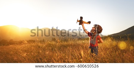 Child pilot aviator with airplane dreams of traveling in summer in nature at sunset