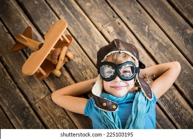 Child Pilot With Vintage Plane Toy On Grunge Wooden Background