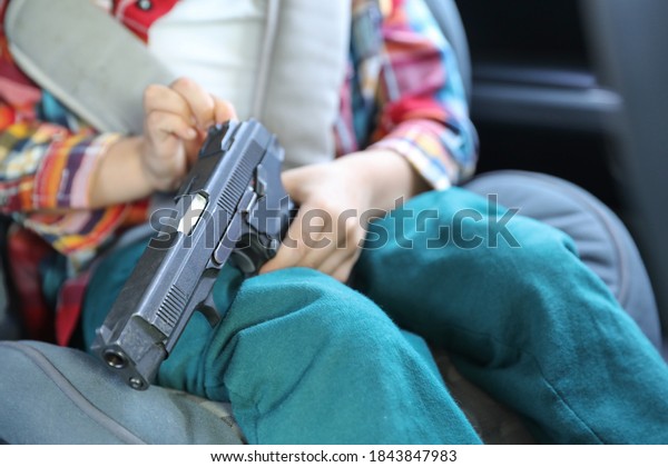 A child with a pistol rides in a car.\
Careless storage of weapons,\
negligence.