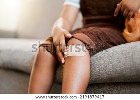 Child with plaster or bandaid, injured and hurt by accident while playing a sport, exercise or outside closeup. Kid with a medical bandage after help on wound, injury or scratch on skin, knee or leg