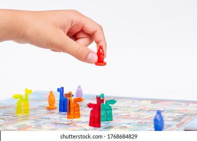 Child Play A Board Game. Child's Hand Holding A Figure Board Game 