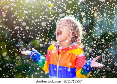 Child Playing In Autumn Rain. Kid With Umbrella. Little Boy Running In A Park In Fall Season. Outdoor Fun For Kids By Any Weather. Rain Waterproof Wear, Boots And Jacket For Children.