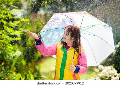 Child Playing In Autumn Rain. Kid With Umbrella. Little Girl Running In A Park In Fall Season. Outdoor Fun For Kids By Any Weather. Rain Waterproof Wear, Boots And Jacket For Children.