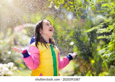 Child Playing In Autumn Rain. Kid With Umbrella. Little Girl Running In A Park In Fall Season. Outdoor Fun For Kids By Any Weather. Rain Waterproof Wear, Boots And Jacket For Children.