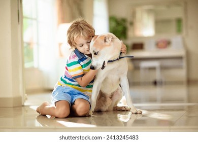 Child playing with baby dog. Kids play with puppy. Little boy and large dog at home. Children and friendship. Kid sitting on the floor with pet. Animal care. - Powered by Shutterstock