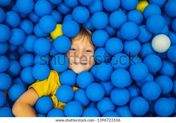 Child playing in ball pit. Colorful toys for\
kids. Kindergarten or preschool play room. Toddler kid at day care\
indoor playground. Balls pool for children. Birthday party for\
active preschooler