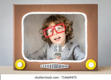 Child Playing With Cardboard Box TV. Kid Having Fun At Home. Video Blogging Concept