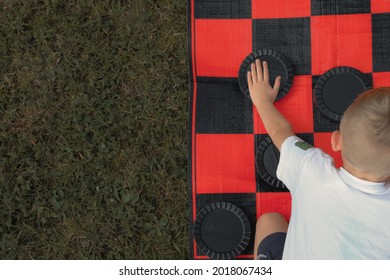 A Child Playing Checkers Outside 